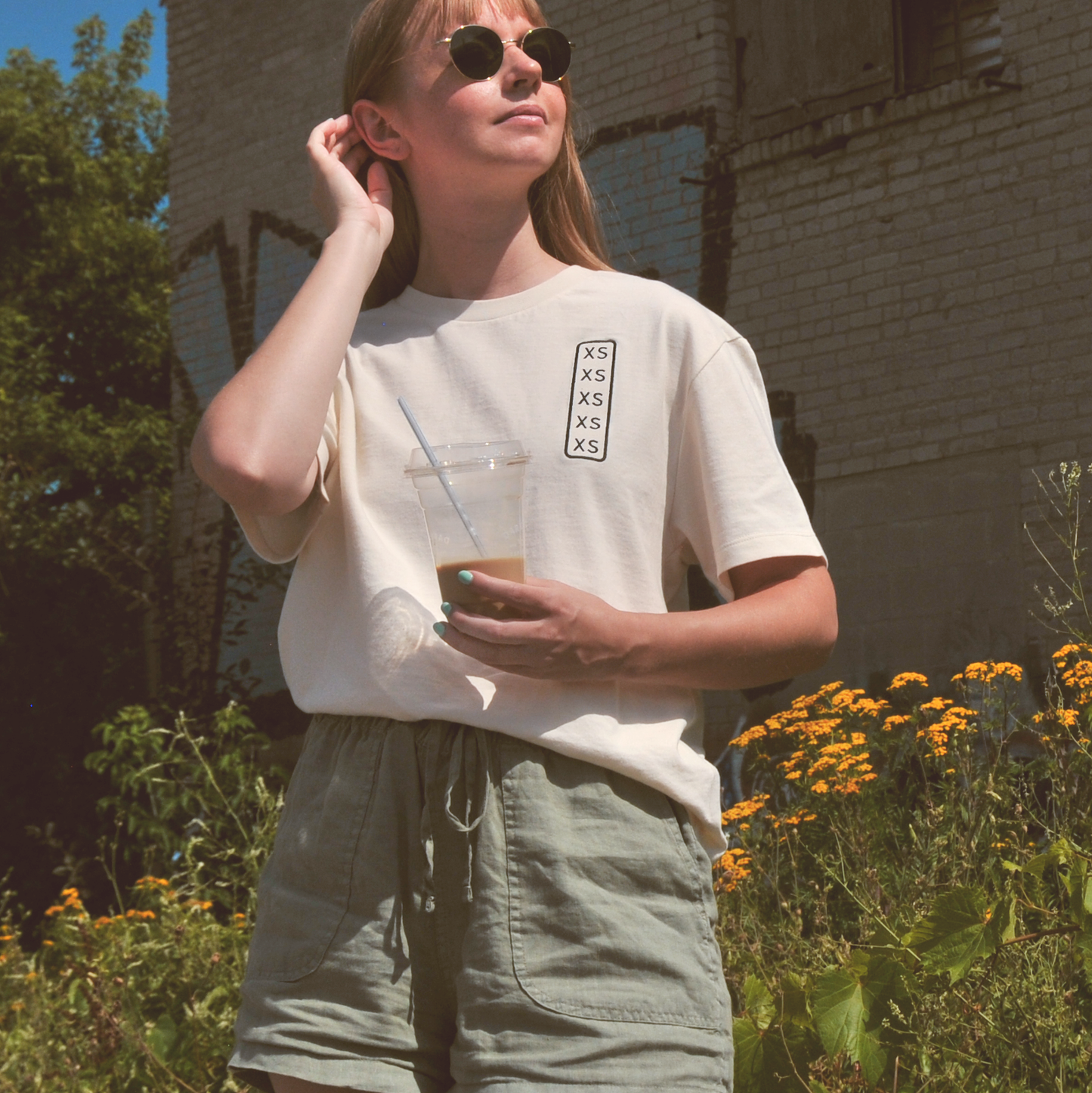 Woman wearing shirt that says XS repeated on it, mimicking a size indication sticker