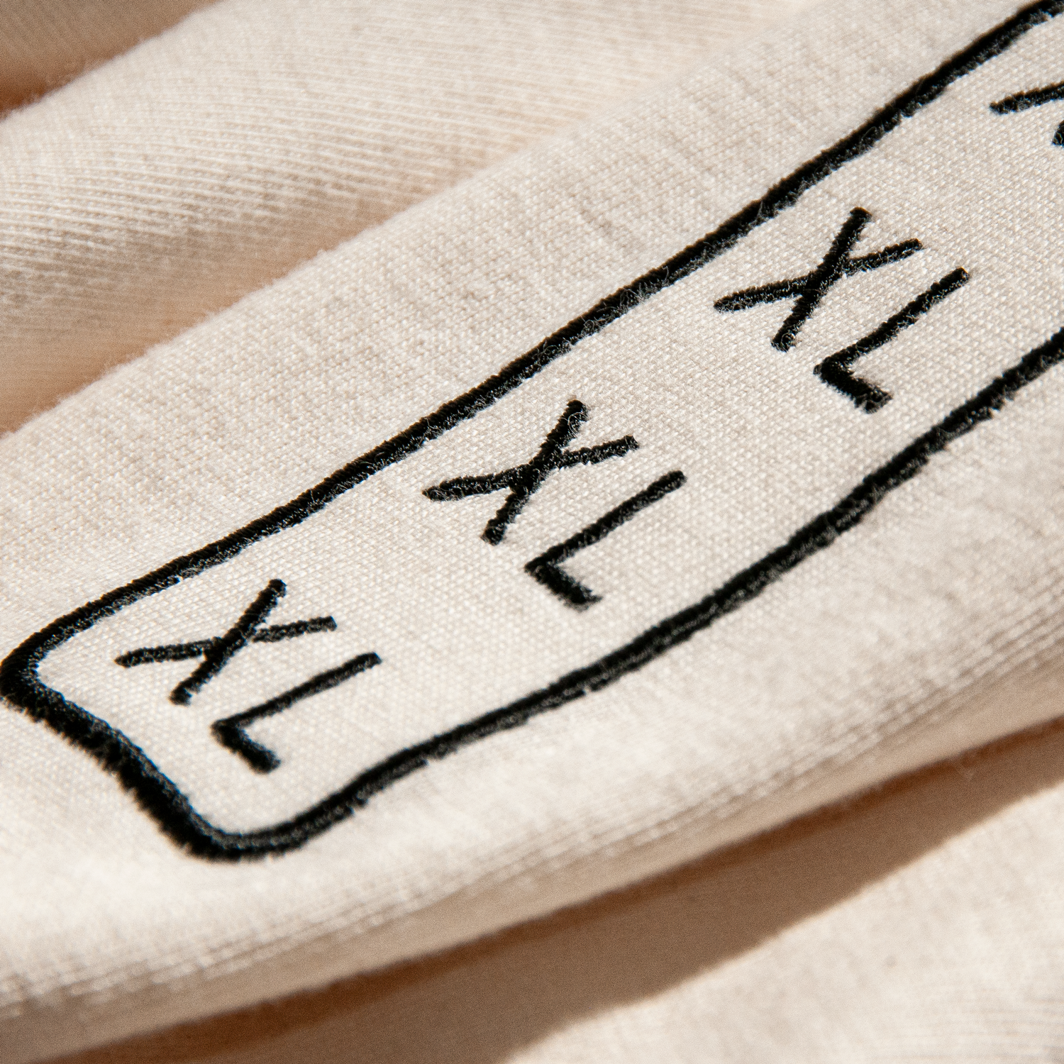 Close-up of XL size indicator for shirt, embroidered permanently in creative design