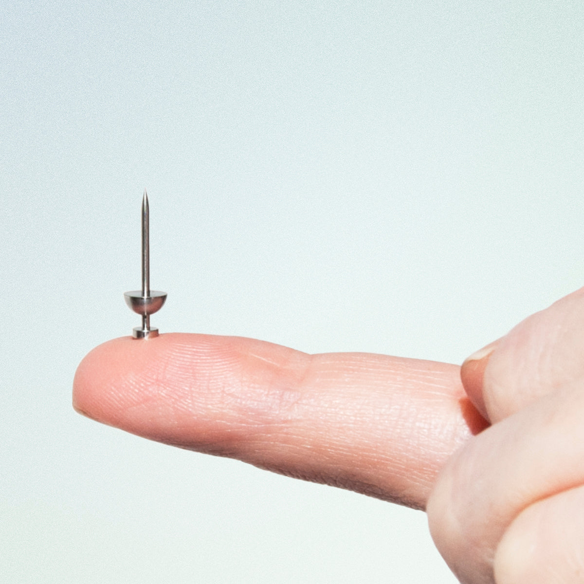 mini metal push pin on finger